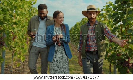 Polite winemaker welcoming guests at vineyard guiding excursion for romantic couple in grape valley of wine region. Honeymoon wine tour. Royalty-Free Stock Photo #1694171377
