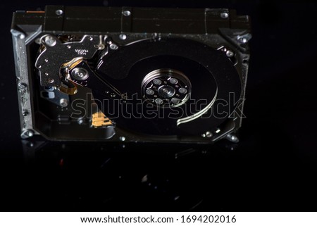 Disassembled hard drive. Spare parts from the hard drive. Photographed close-up against a dark background.
