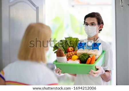 Food delivery during corona virus outbreak. Courier wearing face mask delivering grocery order in coronavirus epidemic. Safe shopping in pandemic. Takeout meal. People stockpile food.