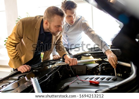 caucasian salesman and consultant look at the hood assemble in car. perfect business class auto represented in dealership