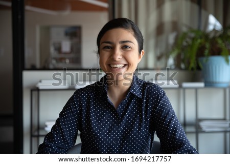 Excited young indian ethnicity woman looking at camera, holding funny conversation with colleagues online, webcam view. Head shot millennial hindu female worker laughing, having fun in office. Royalty-Free Stock Photo #1694217757