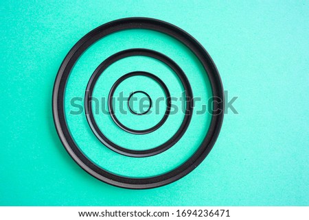 Concentric camera Lens Filter Up and Down Ring Adapters on a teal background