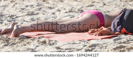 A girl in a swimsuit sunbathes on the shore of a sea beach. Holiday at the resort