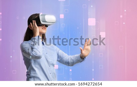 Millennial girl in virtual reality headset touching imaginary screen on color background, collage with copy space. Panorama