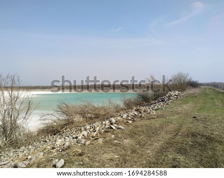  a deserted beach with clear turquoise water on an old lake formed on the site of a chalk quarry
