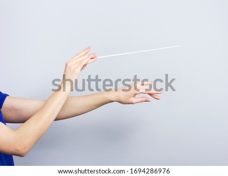 Female hands isolated on gray. Woman conductor. Female hands with a conductors  baton. Royalty-Free Stock Photo #1694286976