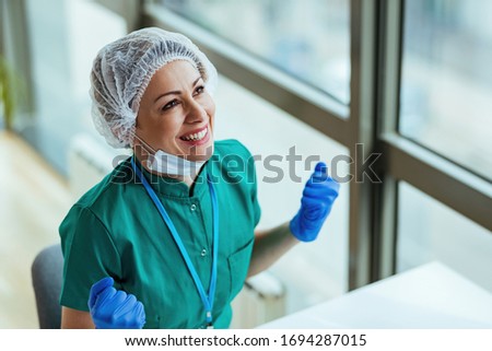 Happy healthcare worker celebrating success while working at clinic.  Royalty-Free Stock Photo #1694287015