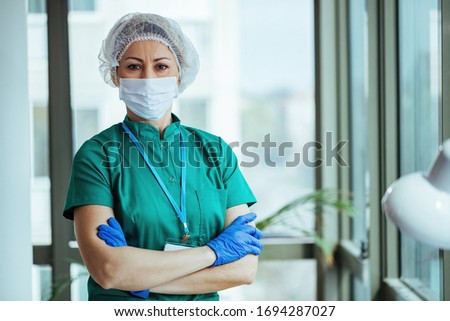 Portrait of surgeon standing with her arms crossed at medical clinic and looking at camera. Royalty-Free Stock Photo #1694287027