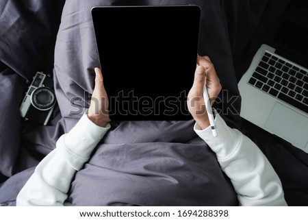 young women lying on her bed and using internet working on tablet and computer laptop ,Working at home concept ,Work from home ,Flat lay 