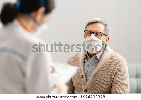Doctor and senior man wearing facemasks during coronavirus and flu outbreak. Virus and illness protection, home quarantine. COVID-2019 Royalty-Free Stock Photo #1694295328