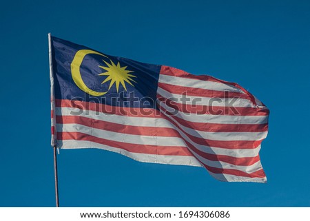 waving Malaysia flag with blue sky as background