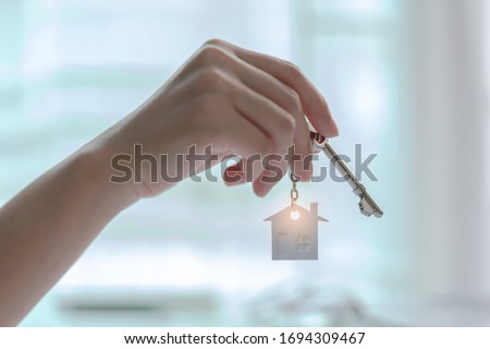 Hand holding house key on house shaped keyring. Concept of Investment property.