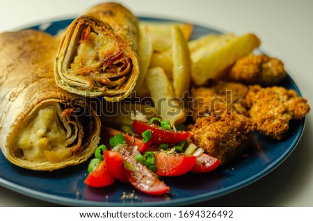 Tortilla wrap with chicken and beechwood smoked bacon served with chicken nuggets and chips, tasty food