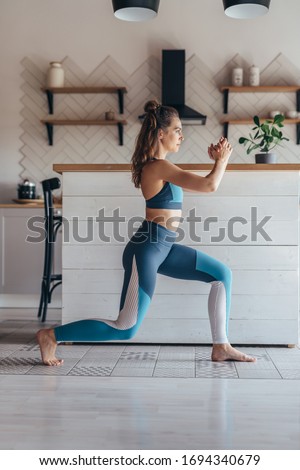 Fit woman exercising at home doing lunges exercise. Royalty-Free Stock Photo #1694340679
