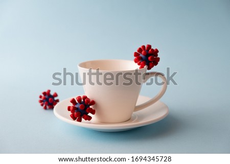 White cup with models of covid-19 virus on blue background. Epidemic coronavirus. Risk of infection COVID-19 concept. Place fo text Royalty-Free Stock Photo #1694345728