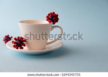 White cup with models of covid-19 virus on blue background. Epidemic coronavirus. Risk of infection COVID-19 concept. Place fo text Royalty-Free Stock Photo #1694345731