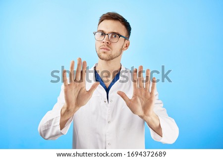 Serious doctor shows a gesture with his hands to the camera, stop panic, keep calm concept isolated on blue background