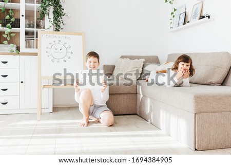 Smiling boy holding Stay Positive draw and sad girl lying on sofa during quarantine covid-19. Coronavirus concept