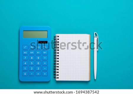 Calculator with notebook on blue background. Education process. Top view. Flat lay