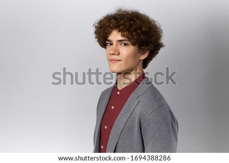 Half profile picture of attractive confident young male with fuzzy hair posing isolated against blank studio wall background with copy space for your text or advertising information, smiling