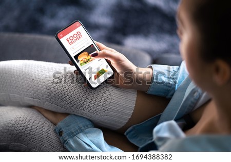 Food delivery app in mobile phone. Restaurant order online. Woman using smartphone to get take away lunch home delivered. Fast courier service. Burger menu mock up in cellphone screen. Royalty-Free Stock Photo #1694388382