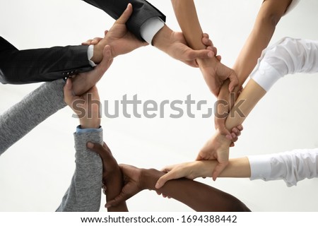 Close up bottom view concept of multiracial business people holding each others wrists, create hands circle. Support and unity team strength and power. Colleagues involved in team building activity. Royalty-Free Stock Photo #1694388442
