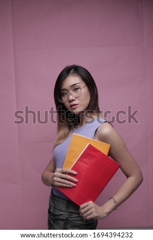 asian girl book on pink background. asian student holding book
