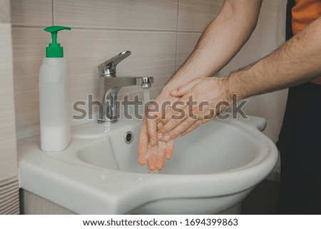 A man washes his hands with liquid soap under running water in the bathroom at home. Prevention of infection