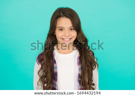 pretty teen girl with long hair, fashion. kid hairdresser concept. Back to school. Studio shot of glad child. childhood happiness. Pleasant emotions. stylish teen girl turquoise background.