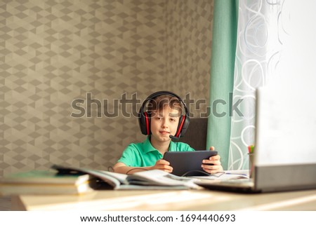 Distance learning child in headphones is watching a lesson on a tablet. Concept online education. Stay at home entertainment.