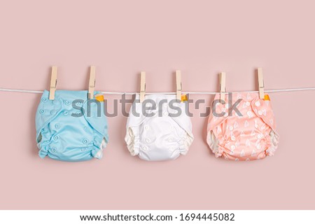 Reusable cloth baby diapers drying on a clothes  line. Eco friendly cloth nappies on a pink background. Sustainable lifestyle. Zero waste concept. Royalty-Free Stock Photo #1694445082