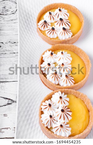 Mini tarts with lemon curd and caramelized meringue on the white wooden table