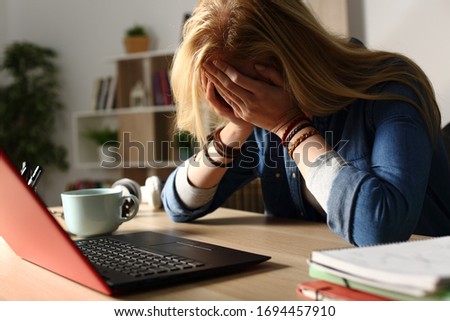 Close up of sad student receiving bad news on laptop sitting on a desk at home at night Royalty-Free Stock Photo #1694457910