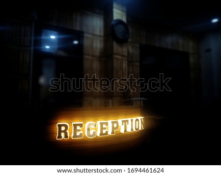 Bokeh shot of name logo of reception for office use with selective focus. Dark background reception desk of a school for advertisement.