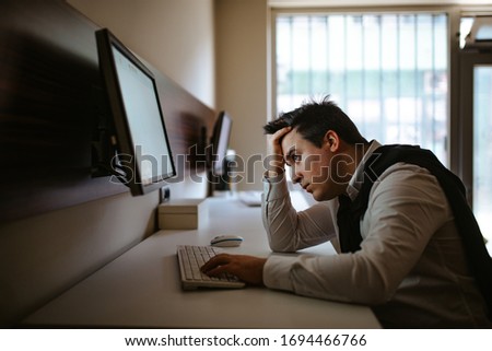 
Young caucasian businessman in the office working on computer. Businessman, work and technology