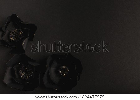 black background with a beautiful gold glittering flowers made of paper, top view, free space for text