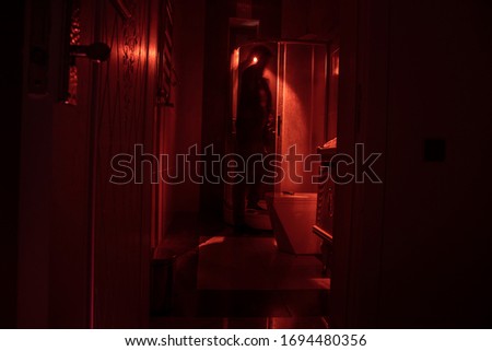 Halloween concept. Horror silhouette of person in shower cabin. Killer maniac inside bathroom with glowing lights. Long exposure