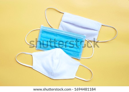 Protective medical mask with cloth masks on yellow background. Top view