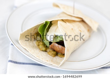 Tortilla served with fried sausage and green peas