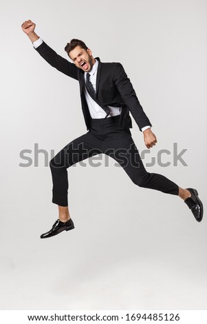 Portrait of a happy businessman jumping in air against isolated white background.