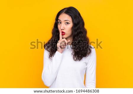 Mixed race woman over isolated yellow background doing silence gesture