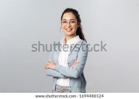 Education, women and lifestyle concept. Attractive asian female entrepreneur, girl tutor smiling satisfied, cross hands chest, pleased help customer with any question, grey background