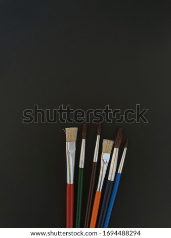 Set of paint brushes in various colours, isolated on a black background. Useful in school, artistic, educational and cultural concepts. Background texture for templates with copy space.
