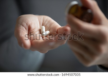 Close up of young woman hold pills in hand take prescribed medicine feel unwell unhealthy, sick female patient consider having antibiotic antidepressants or daily dose of vitamins, medication concept Royalty-Free Stock Photo #1694507035