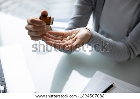 Close up top view of female employee take daily dosage of prescribed vitamins or medication at work, unhealthy woman worker having antibiotics or antidepressant pill feeling sick unwell at workplace Royalty-Free Stock Photo #1694507086