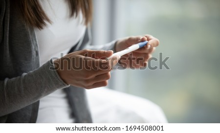 Close up of young woman hold in hands positive or negative pregnancy test thinking pondering, millennial female expecting baby undergo fertility infertility treatment, IVF, future maternity concept Royalty-Free Stock Photo #1694508001