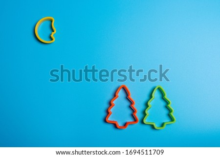 Colored cookie cutters for the preparation of a two Christmas tree and the moon on a blue background. Culinary concept. Flat lay with copyspace.