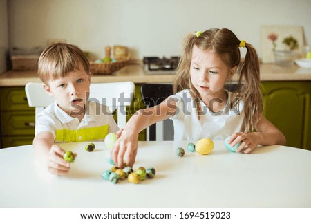 Easter holiday - cute cheerful children holding decorated eggs at home. Little girl and boy - having fun and celebrating feast