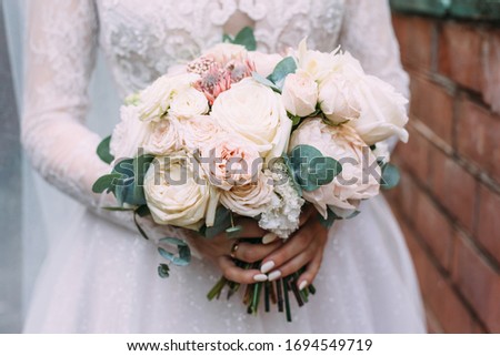 The bride holds the wedding bouquet with both hands. Pink and white flowers, close-up. Wedding day