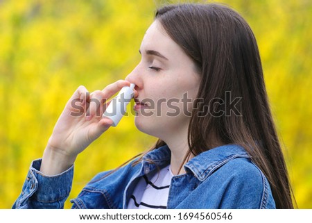  Pollen allergy, Teenager gir using nose inhaler in park
